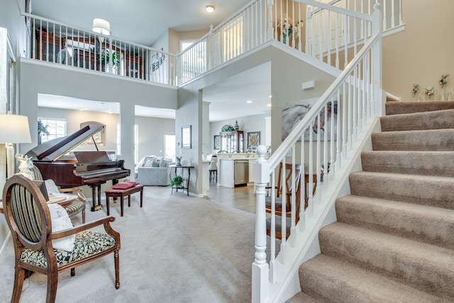 interior space with baseboards, a healthy amount of sunlight, a high ceiling, and stairs