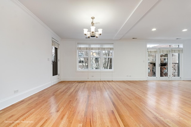 unfurnished room featuring a chandelier, light wood-type flooring, ornamental molding, and baseboards