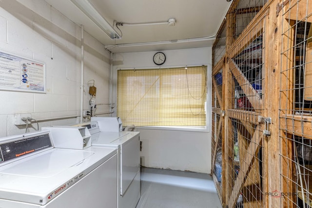 common laundry area featuring concrete block wall and washing machine and clothes dryer