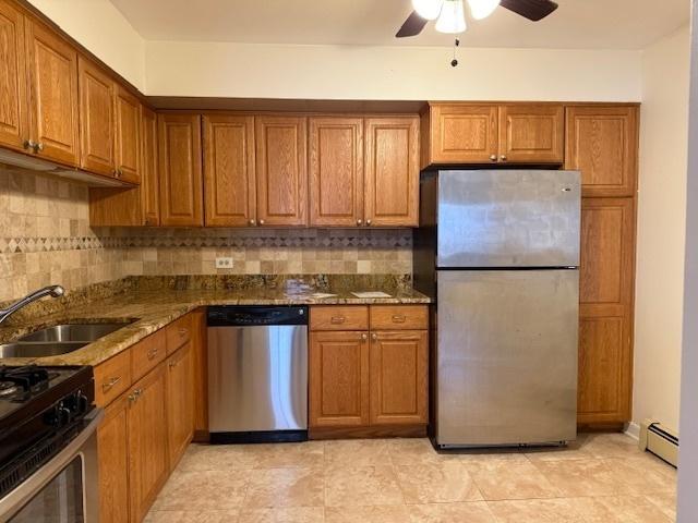 kitchen featuring a baseboard heating unit, a sink, appliances with stainless steel finishes, decorative backsplash, and brown cabinetry