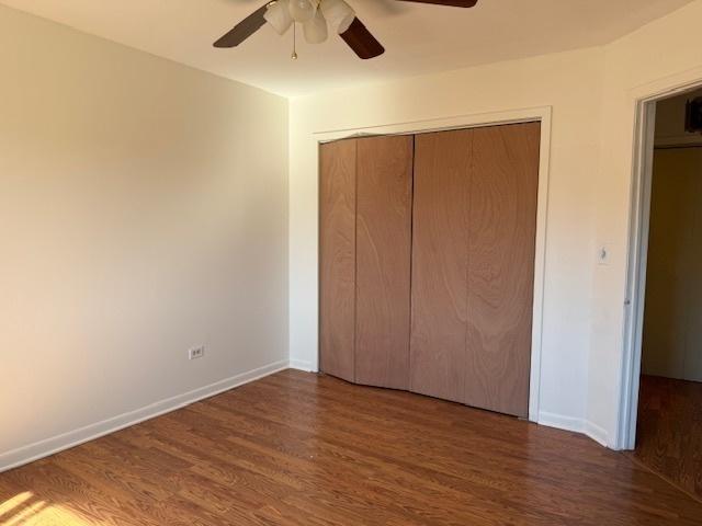 unfurnished bedroom featuring a ceiling fan, a closet, baseboards, and wood finished floors