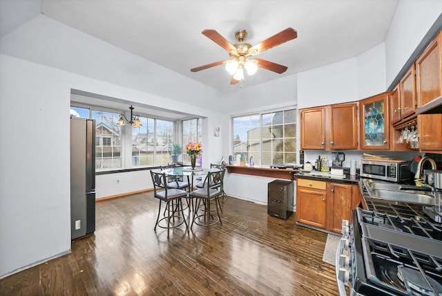 kitchen with dark wood-style floors, stainless steel appliances, dark countertops, and brown cabinets