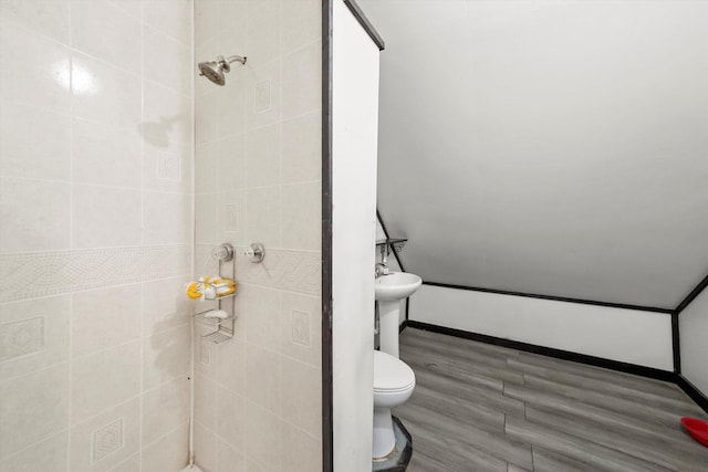 bathroom featuring tiled shower, toilet, and wood finished floors