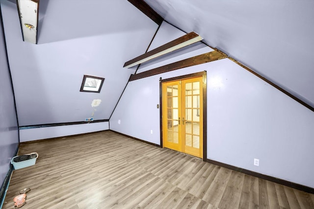 additional living space featuring french doors, vaulted ceiling with beams, baseboards, and wood finished floors