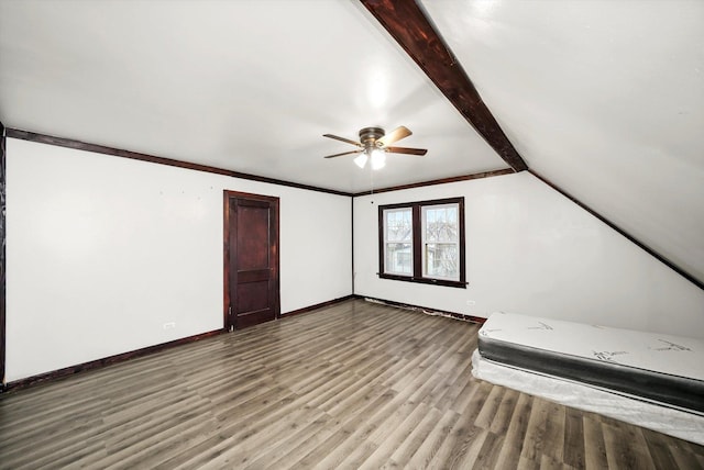 interior space featuring lofted ceiling with beams, ceiling fan, baseboards, and wood finished floors