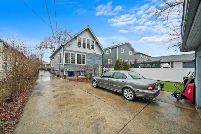 view of front of house featuring concrete driveway and fence