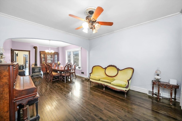 dining space with ornamental molding, hardwood / wood-style floors, arched walkways, and a wood stove