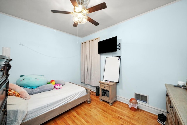 bedroom with visible vents, baseboards, light wood-style flooring, ceiling fan, and ornamental molding