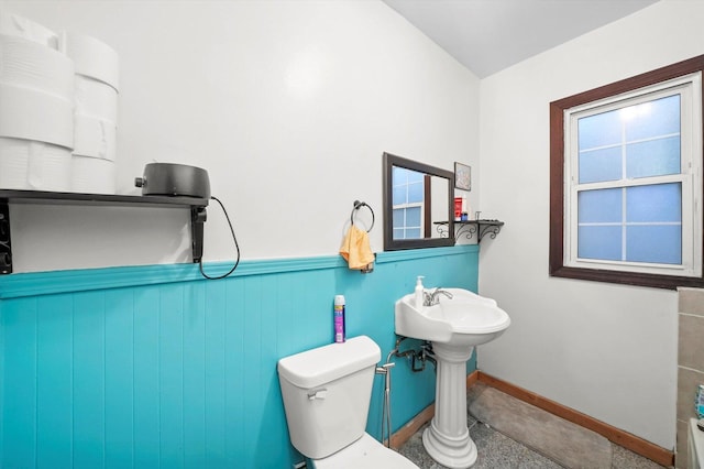 bathroom featuring wainscoting, baseboards, and toilet