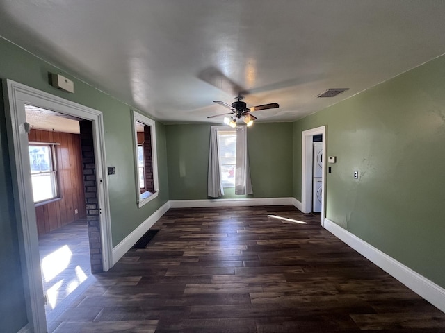 spare room featuring plenty of natural light, visible vents, dark wood finished floors, and baseboards