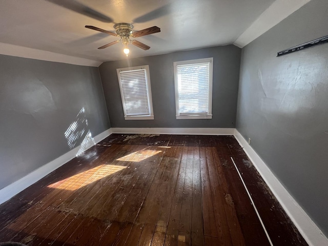 empty room with lofted ceiling, ceiling fan, wood-type flooring, and baseboards