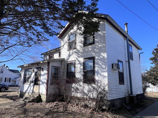 view of front facade with entry steps and a wall unit AC