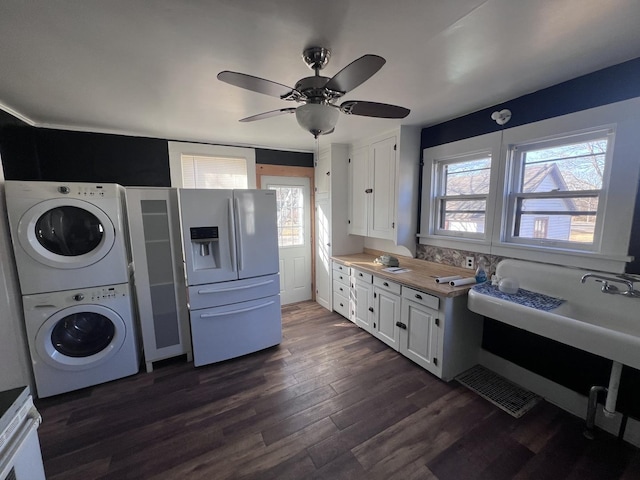 kitchen with white appliances, white cabinets, dark wood finished floors, light countertops, and stacked washing maching and dryer