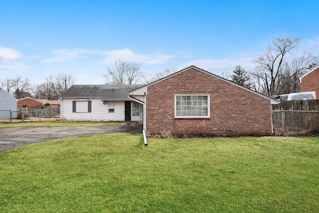 back of house with brick siding, fence, aphalt driveway, and a yard