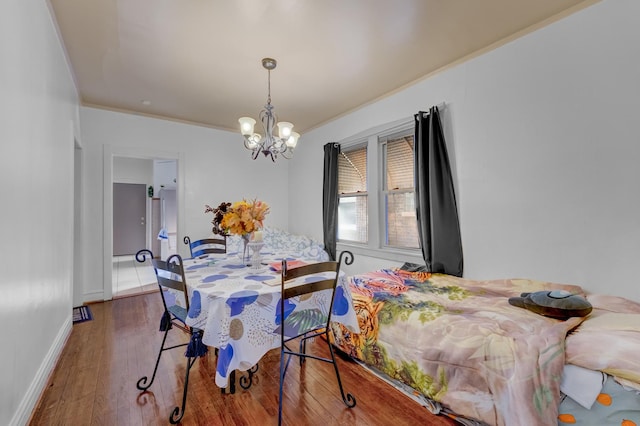 dining space with a chandelier, ornamental molding, wood finished floors, and baseboards