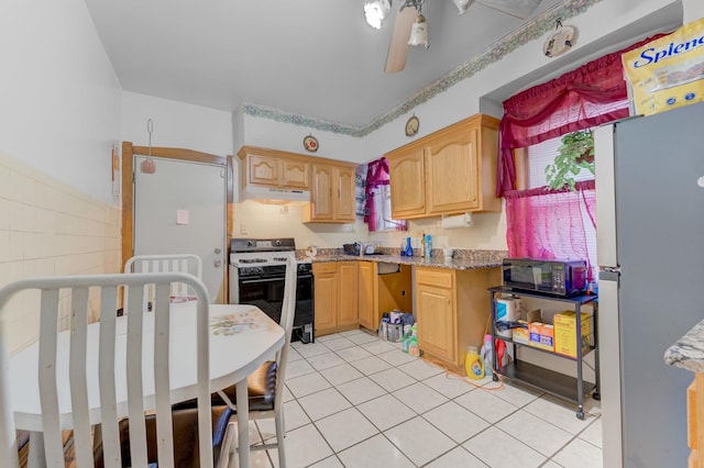 kitchen featuring freestanding refrigerator, light tile patterned floors, black microwave, electric range, and under cabinet range hood