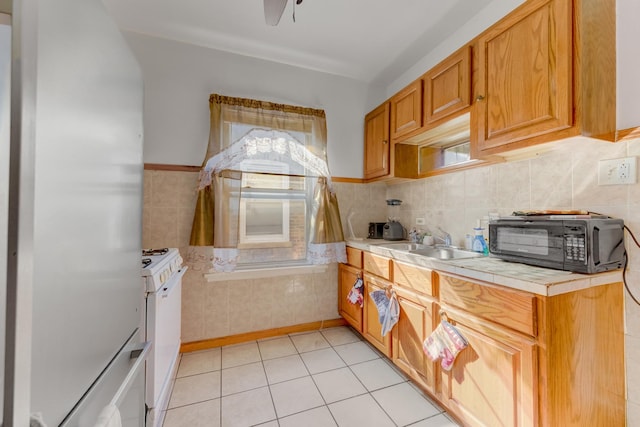 kitchen with light tile patterned floors, white range with gas stovetop, a sink, black microwave, and fridge