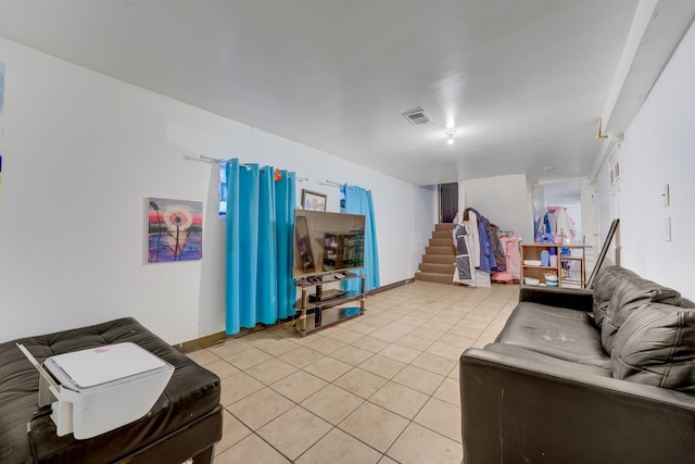 living room featuring visible vents, baseboards, light tile patterned floors, and stairs