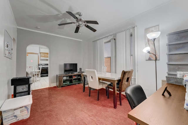 carpeted office featuring arched walkways, crown molding, and ceiling fan