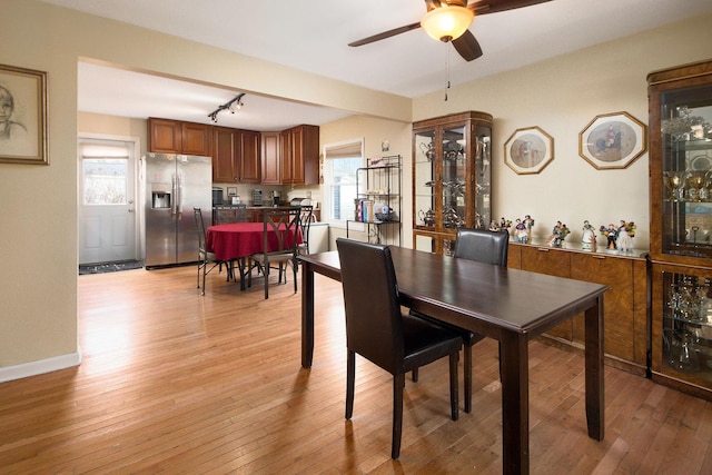 dining space featuring rail lighting, baseboards, light wood-style floors, and a ceiling fan