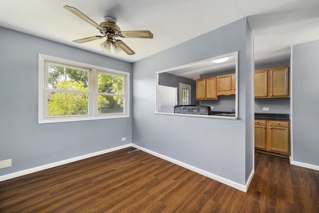 kitchen with baseboards, brown cabinetry, dark wood finished floors, dark countertops, and ceiling fan