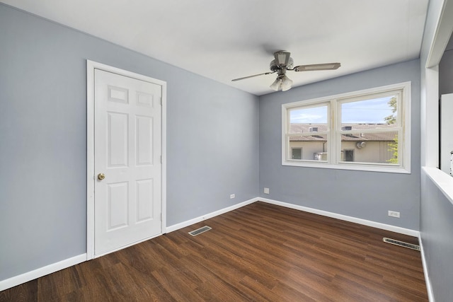 empty room featuring dark wood finished floors, visible vents, and baseboards