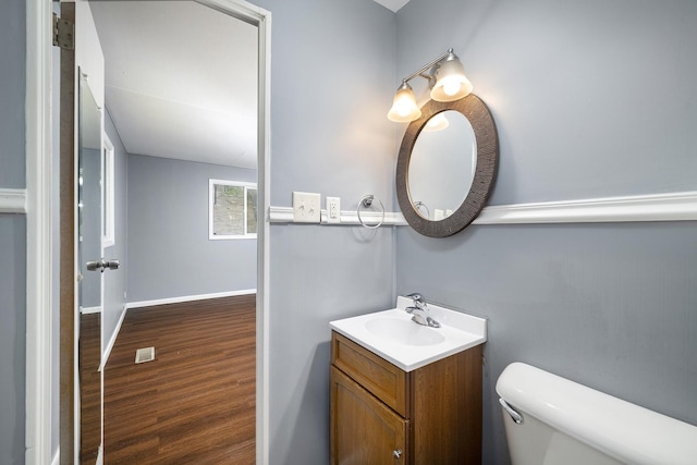 bathroom with vanity, wood finished floors, toilet, and baseboards