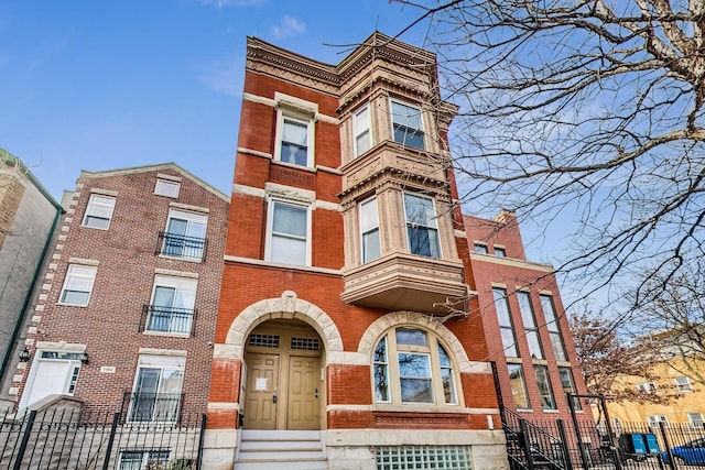 view of front of house featuring brick siding and fence