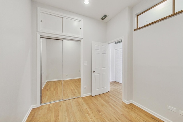 unfurnished bedroom with light wood finished floors, baseboards, visible vents, and a closet