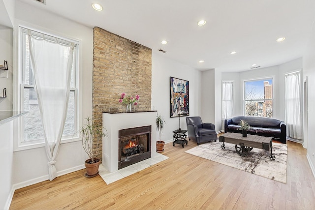 living room featuring a large fireplace, visible vents, wood finished floors, and recessed lighting