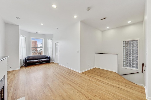 interior space with an upstairs landing, recessed lighting, baseboards, and light wood finished floors