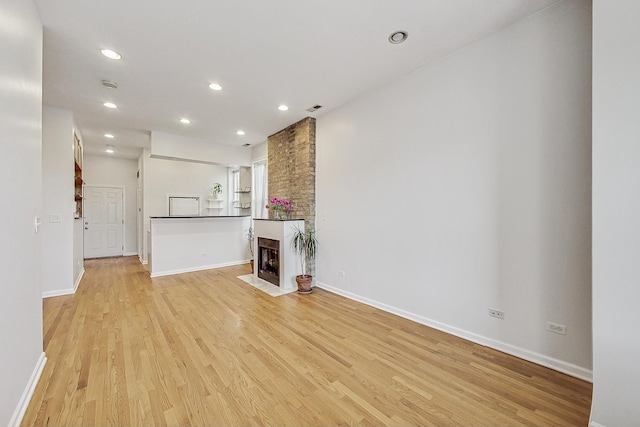 unfurnished living room with recessed lighting, baseboards, light wood finished floors, and a multi sided fireplace