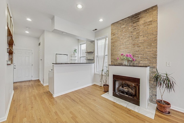 interior space featuring dark countertops, light wood finished floors, a fireplace with flush hearth, and visible vents