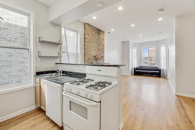 kitchen with dark countertops, white appliances, a sink, and light wood-style flooring