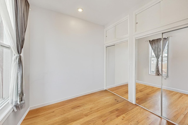 unfurnished bedroom featuring light wood finished floors, baseboards, and recessed lighting