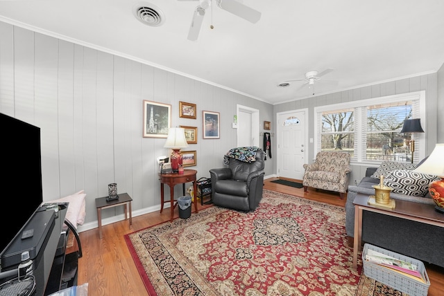 living room featuring visible vents, baseboards, ornamental molding, wood finished floors, and a ceiling fan