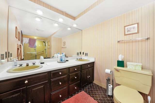 full bathroom featuring double vanity, toilet, a stall shower, and a sink