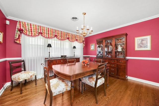 dining room with visible vents, a notable chandelier, wood finished floors, and crown molding