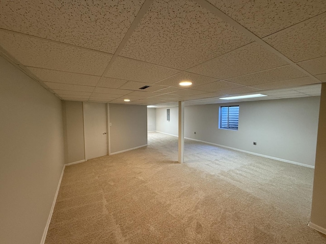 below grade area with carpet, a paneled ceiling, and baseboards