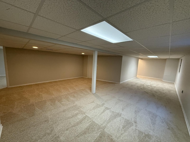 finished basement with carpet, a paneled ceiling, and baseboards