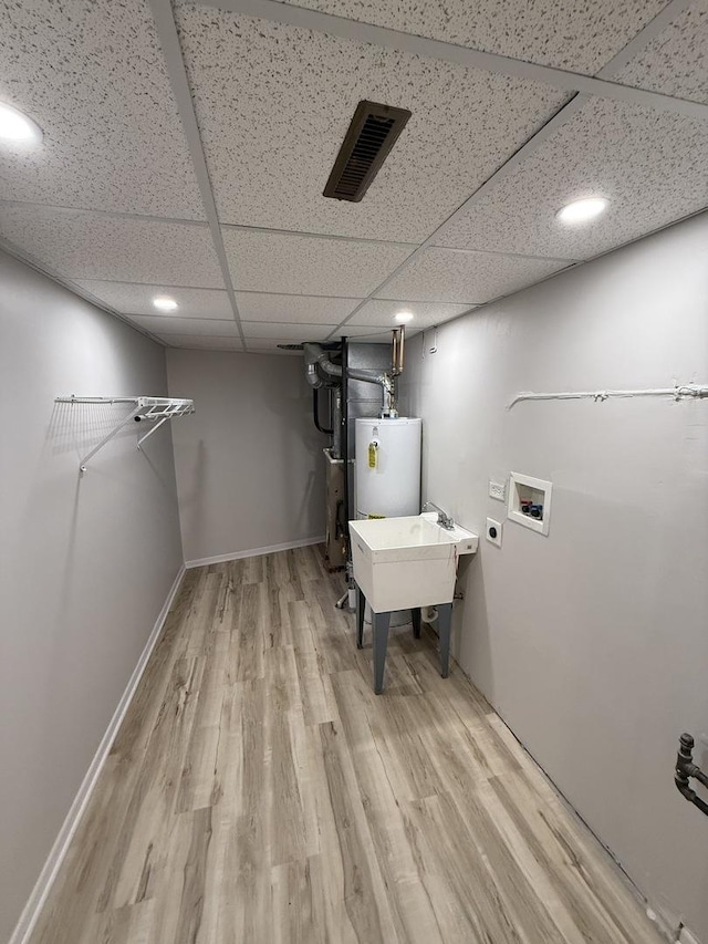 washroom with washer hookup, water heater, visible vents, wood finished floors, and laundry area