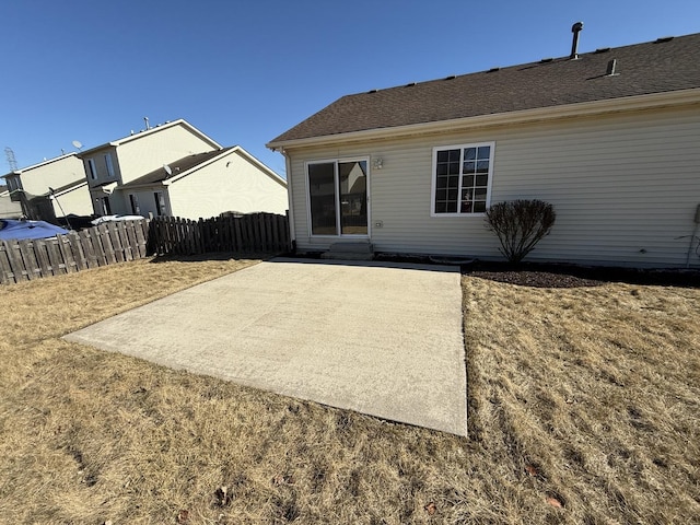 rear view of property featuring entry steps, a shingled roof, a patio area, and fence