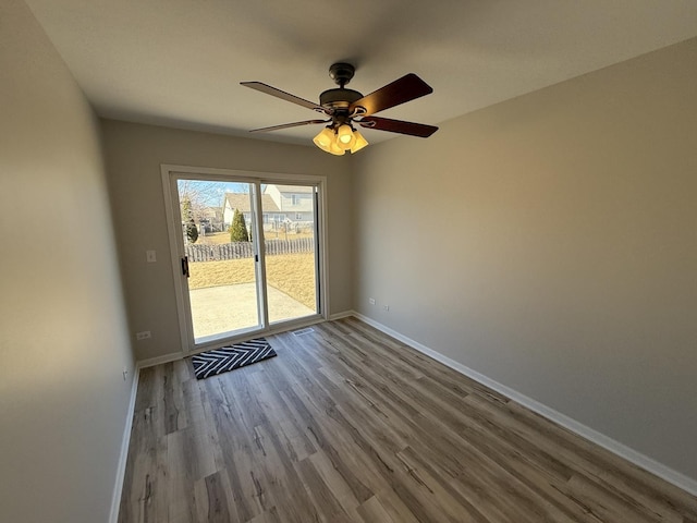 spare room featuring wood finished floors, a ceiling fan, and baseboards