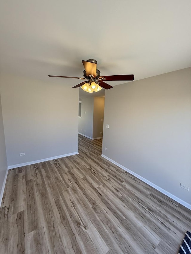 spare room featuring ceiling fan, baseboards, and wood finished floors