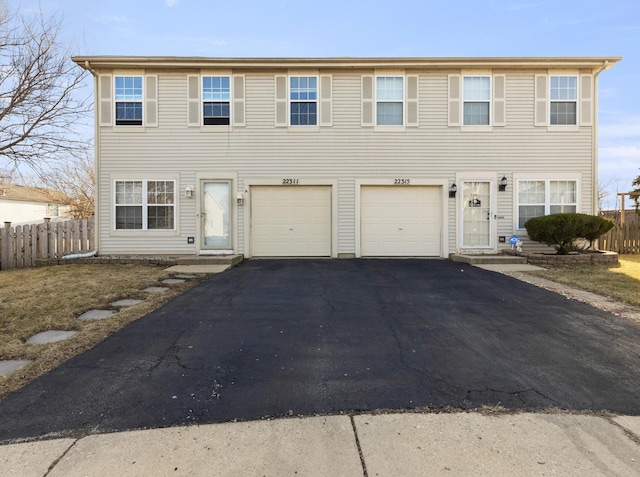 view of front of property featuring aphalt driveway, an attached garage, and fence