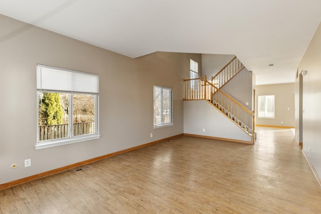 empty room featuring stairway, baseboards, visible vents, and light wood finished floors