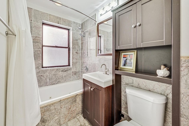 full bath with tiled shower / bath combo, toilet, tile walls, and vanity