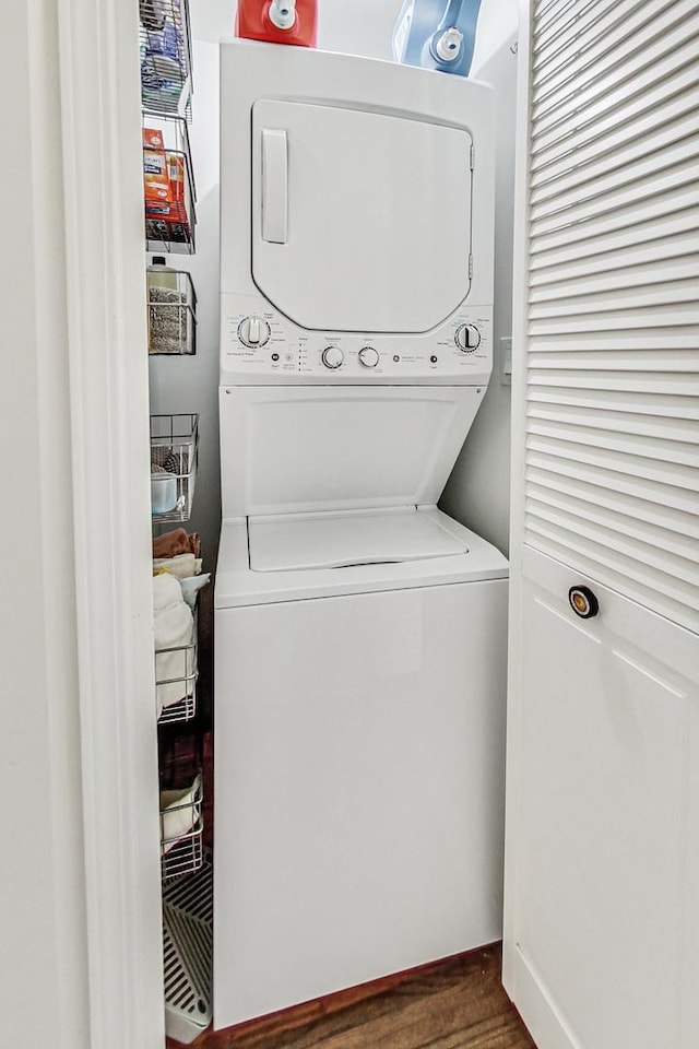 laundry room with laundry area, dark wood-style flooring, and stacked washing maching and dryer