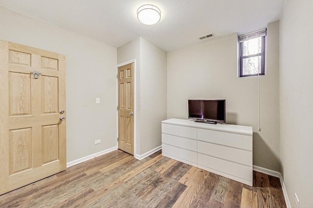 bedroom with wood finished floors, visible vents, and baseboards