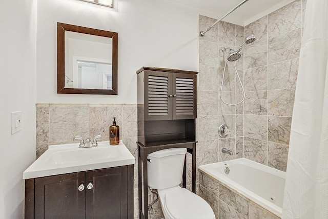 bathroom featuring toilet, tiled shower / bath combo, vanity, and tile walls